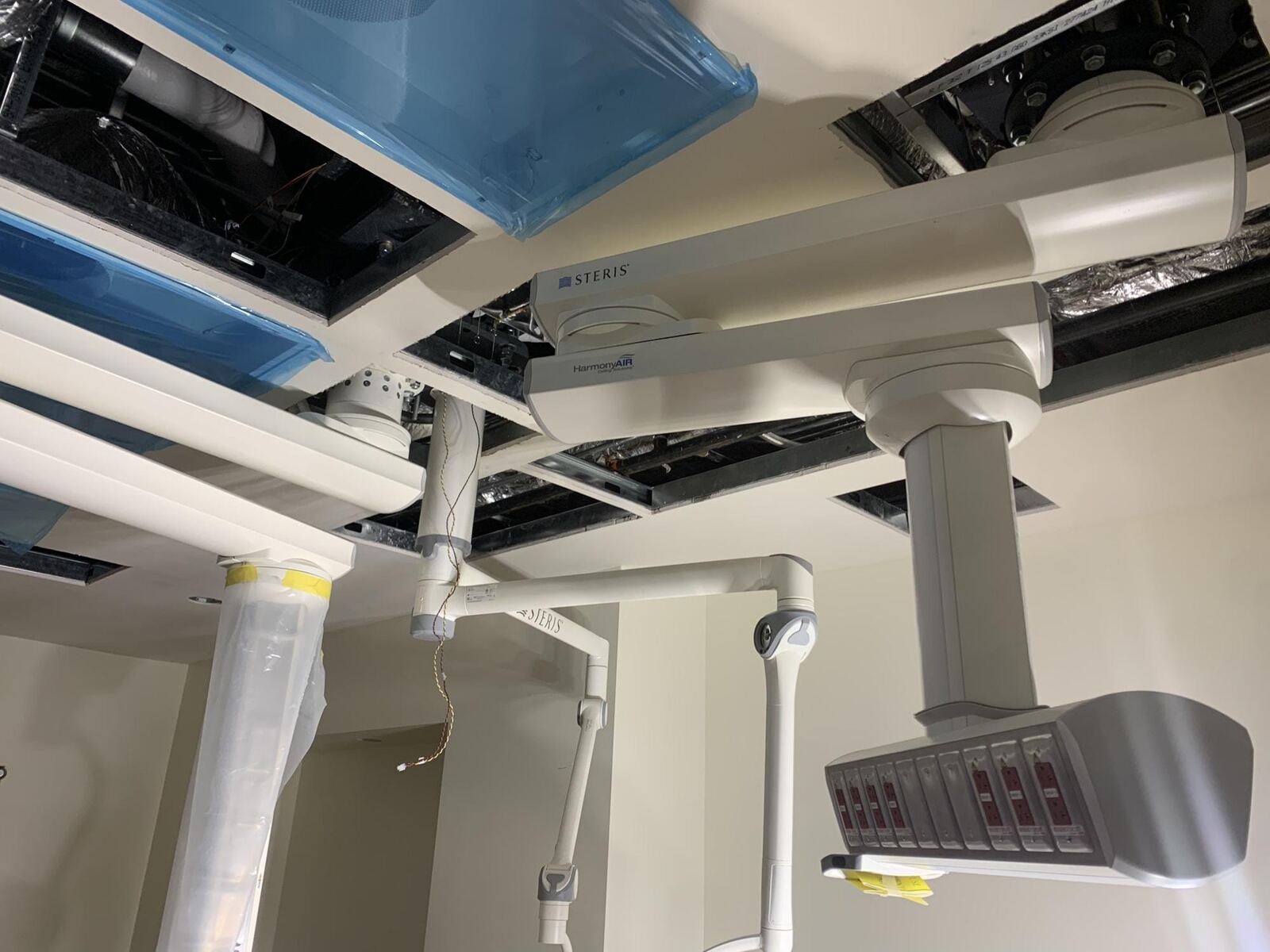 Ceiling-mounted surgical booms and equipment plates in a hospital operating room