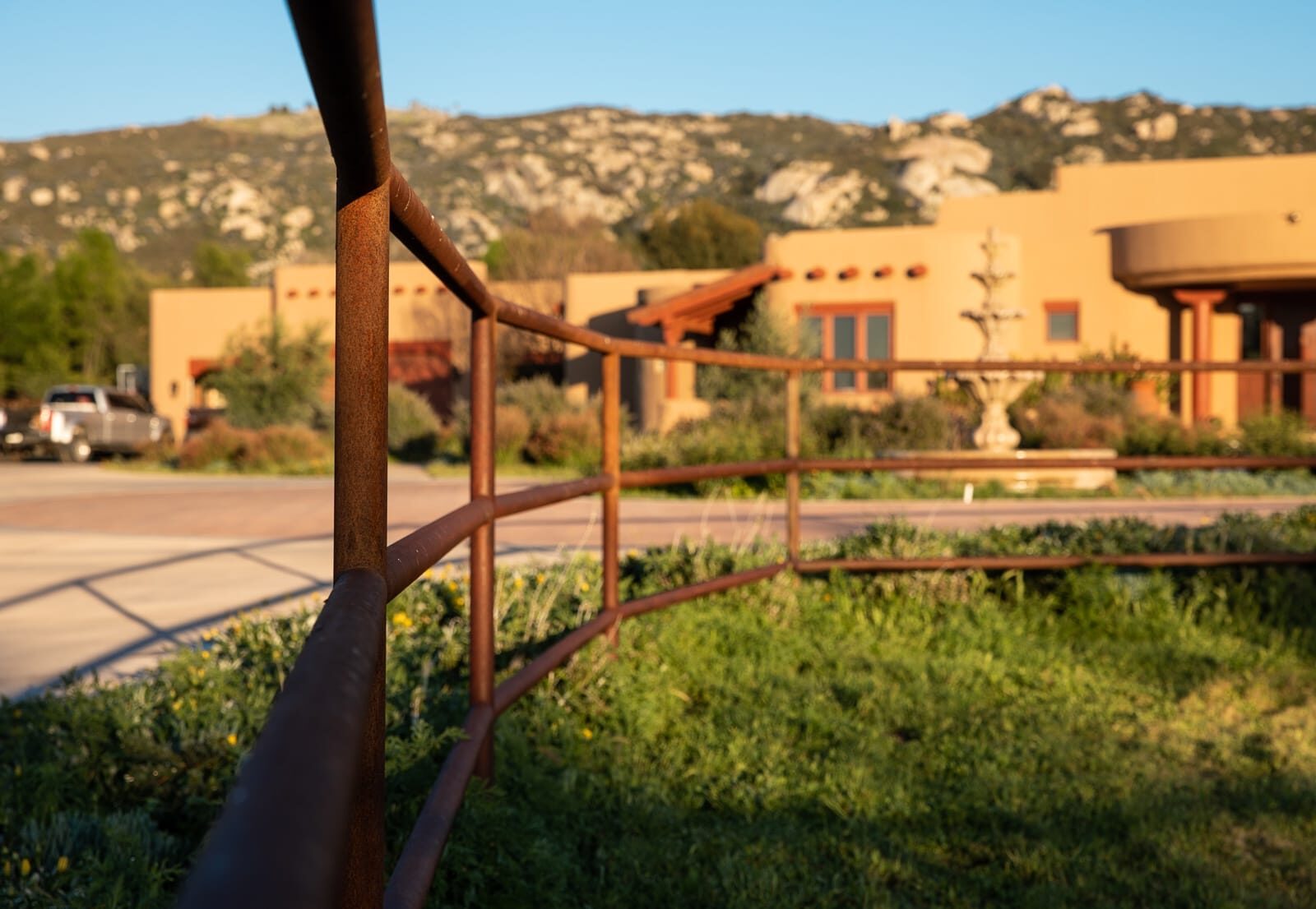 Weathered drill-pipe ranch fencing across a custom horse property, finished installation