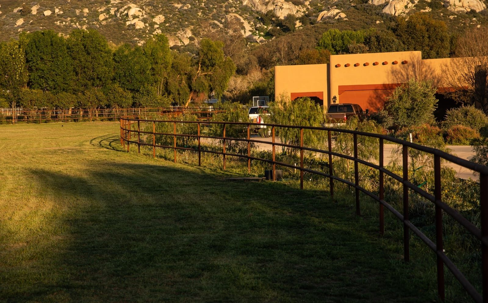 Weathered drill-pipe ranch fencing across a custom horse property, close-up