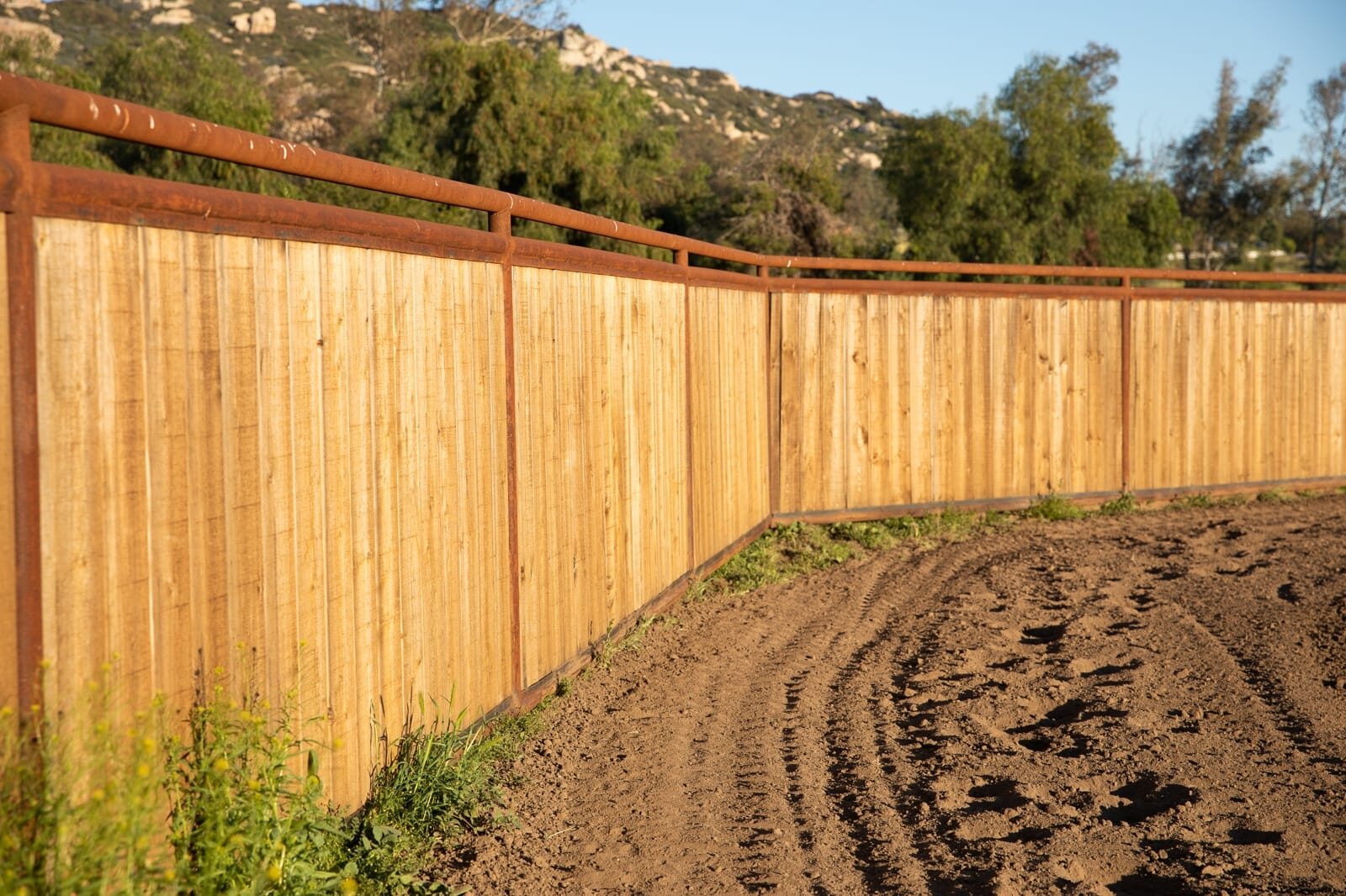 Weathered drill-pipe ranch fencing across a custom horse property